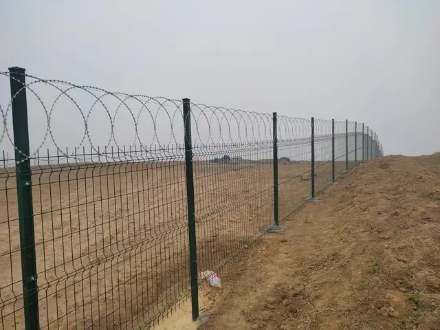 Arazi sınırında panel çit üstü jiletli tel
